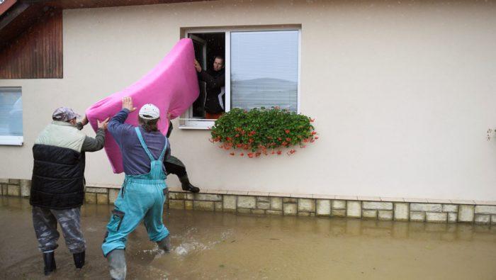 muž vyťahuje matrac cez okno počas povodne