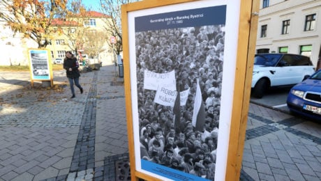 Chodkyňa kráča popri vystavených fotografiách z novembrovej revolúcie v novembri 1989