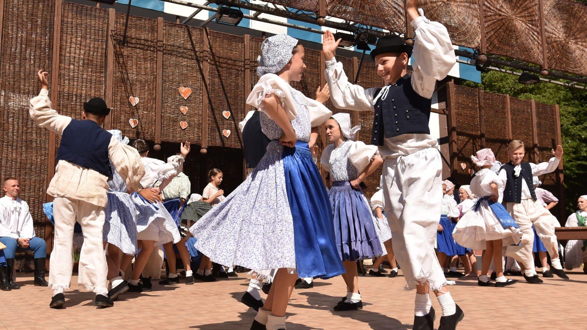 Členovia folklórneho súboru tancujú na pódiu.