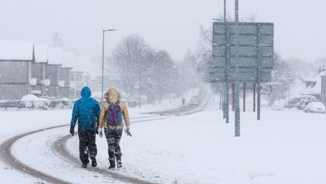 na snímke je dvojica ľudí, ktorí idú po zasneženom meste