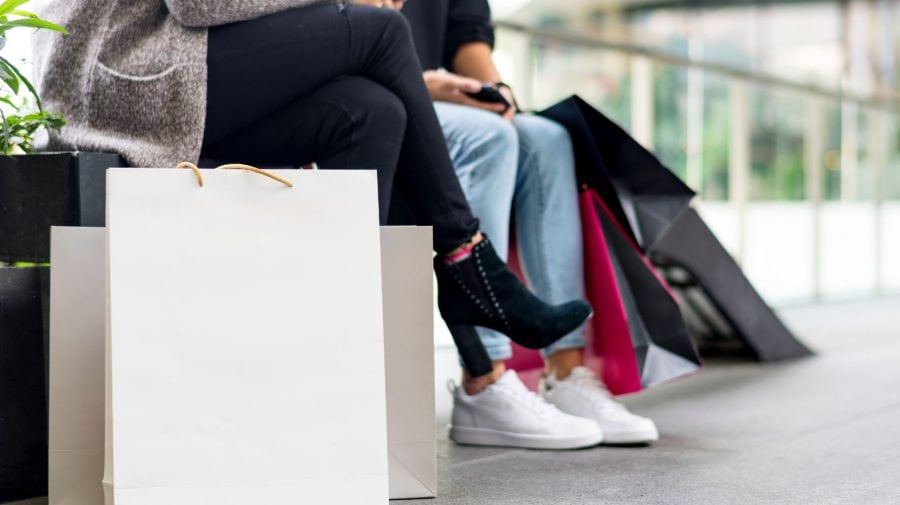 Žena s mužom na lavičke s nákupnými taškami.