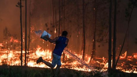 Muž sa snaží uhasiť lesný požiar.
